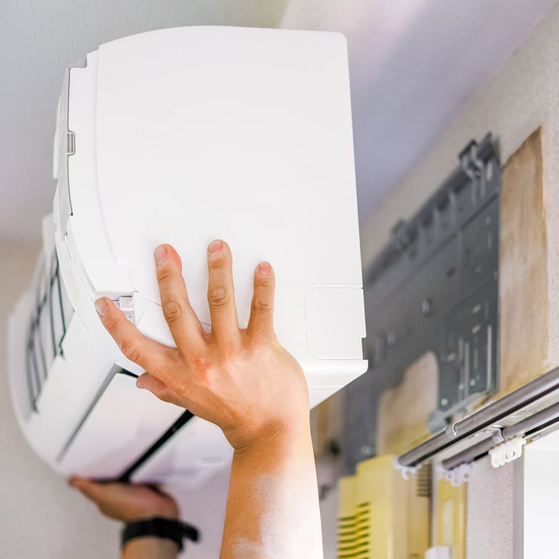 Photo d'une personne fixant un climatiseur au dessus d'une fenêtre